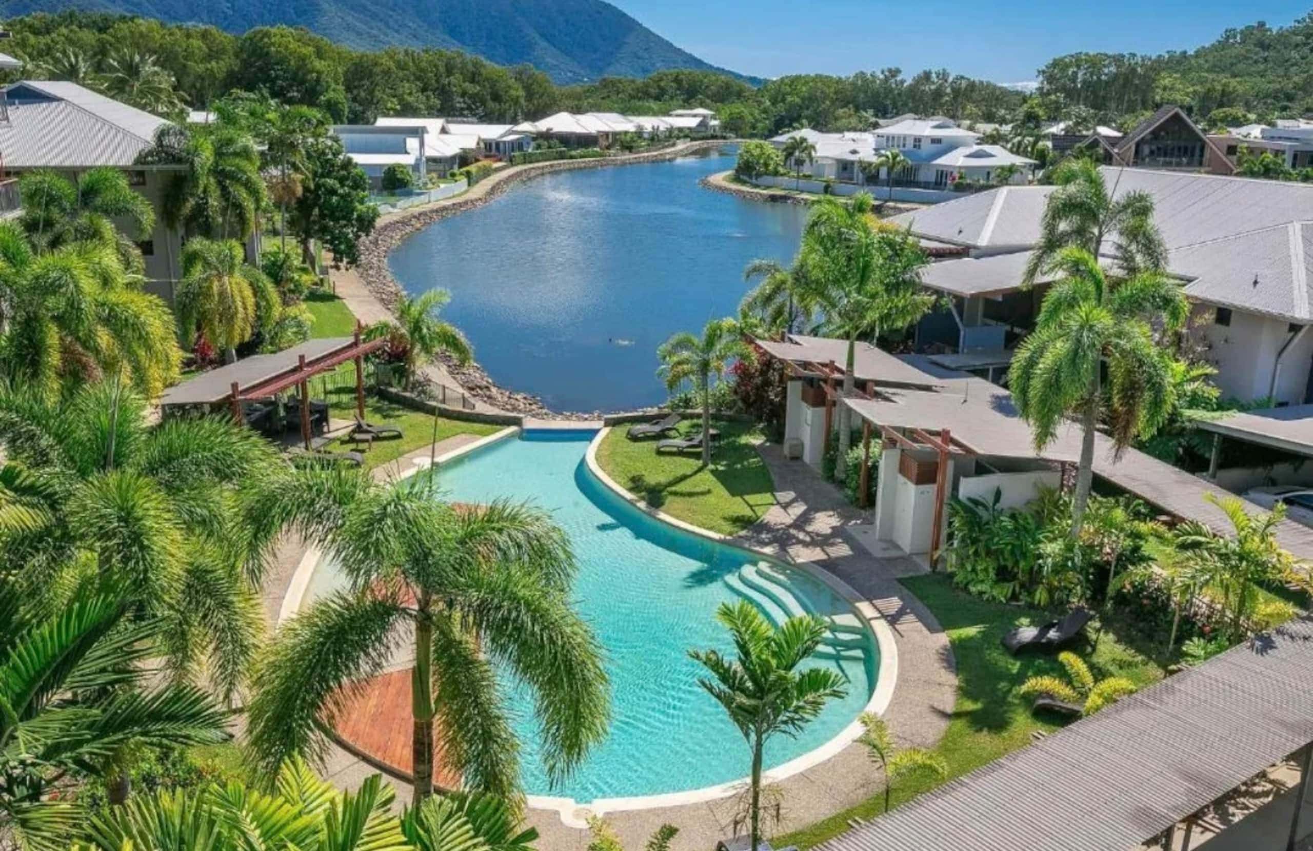Aerial view of the estate resort pool winding between palms beside the lagoon
