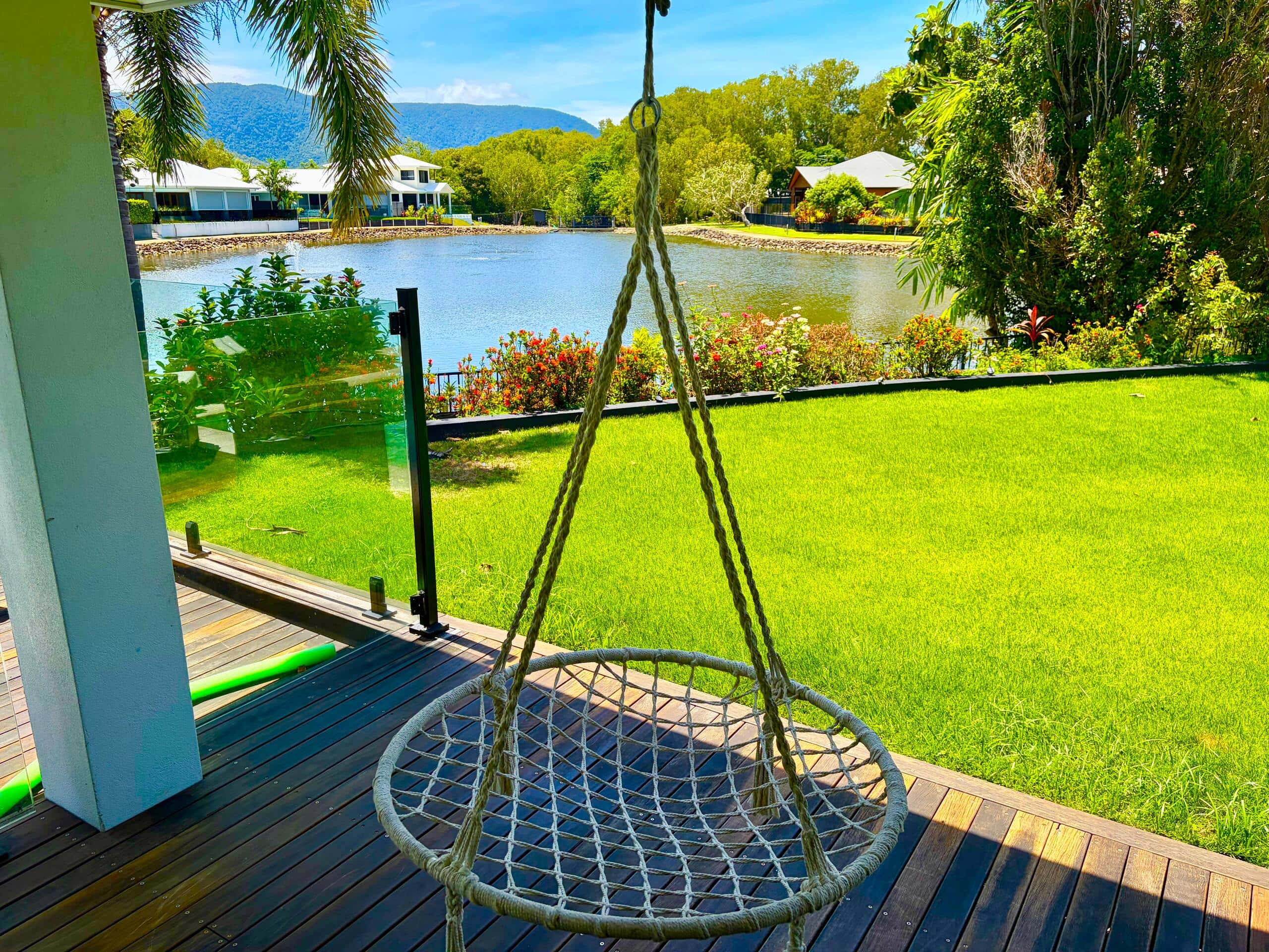 Rope swing chair on the deck looking across the lawn to the lagoon fountain