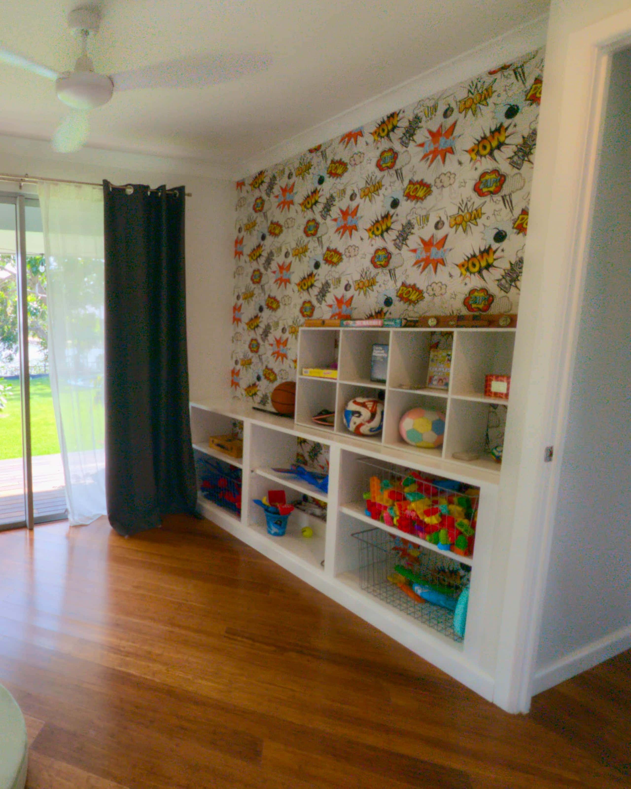 Dedicated playroom with comic-print wall and shelves of toys, balls, blocks and board games