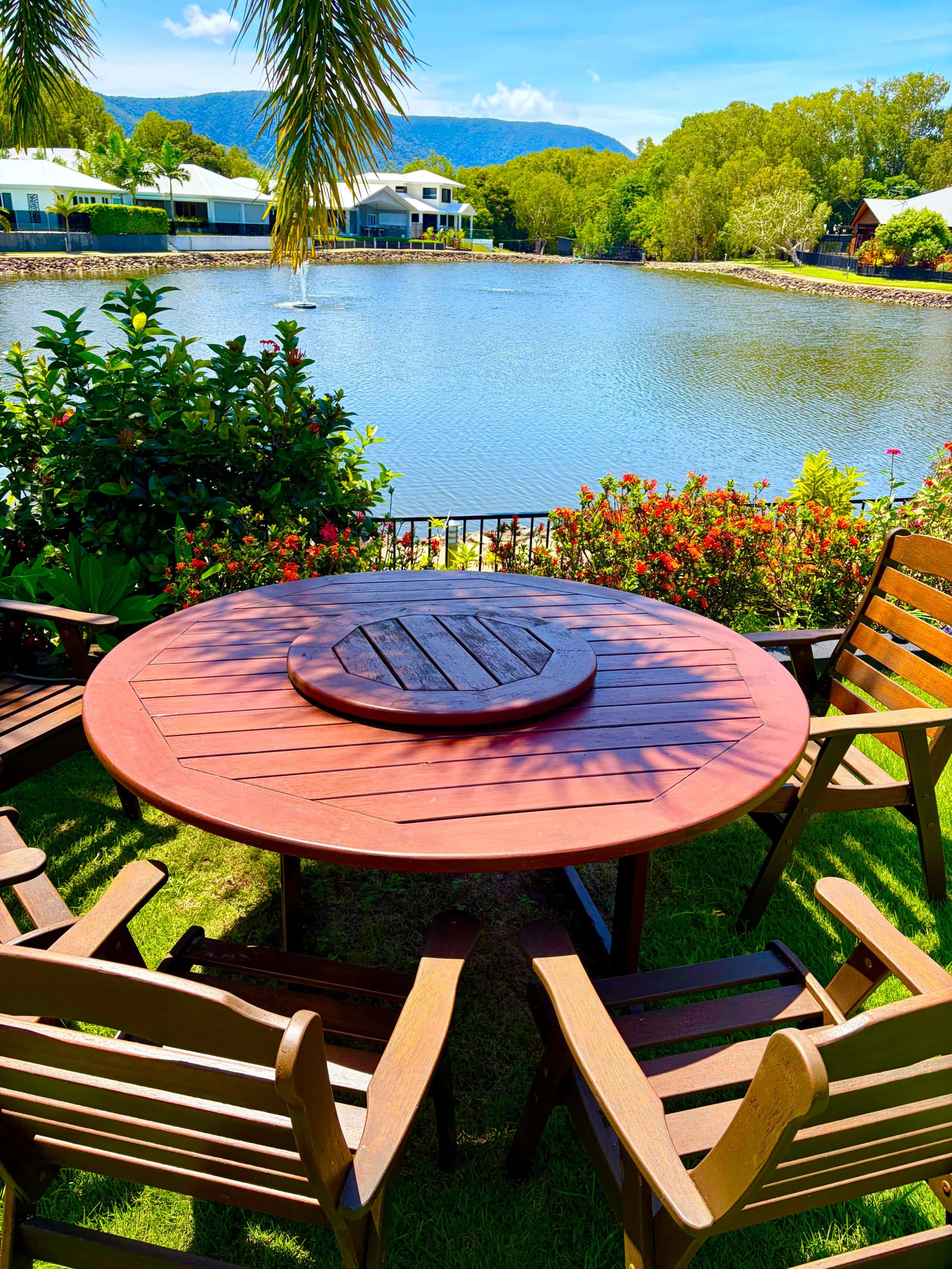 Round timber dining table on the lawn overlooking the lagoon fountain and mountains