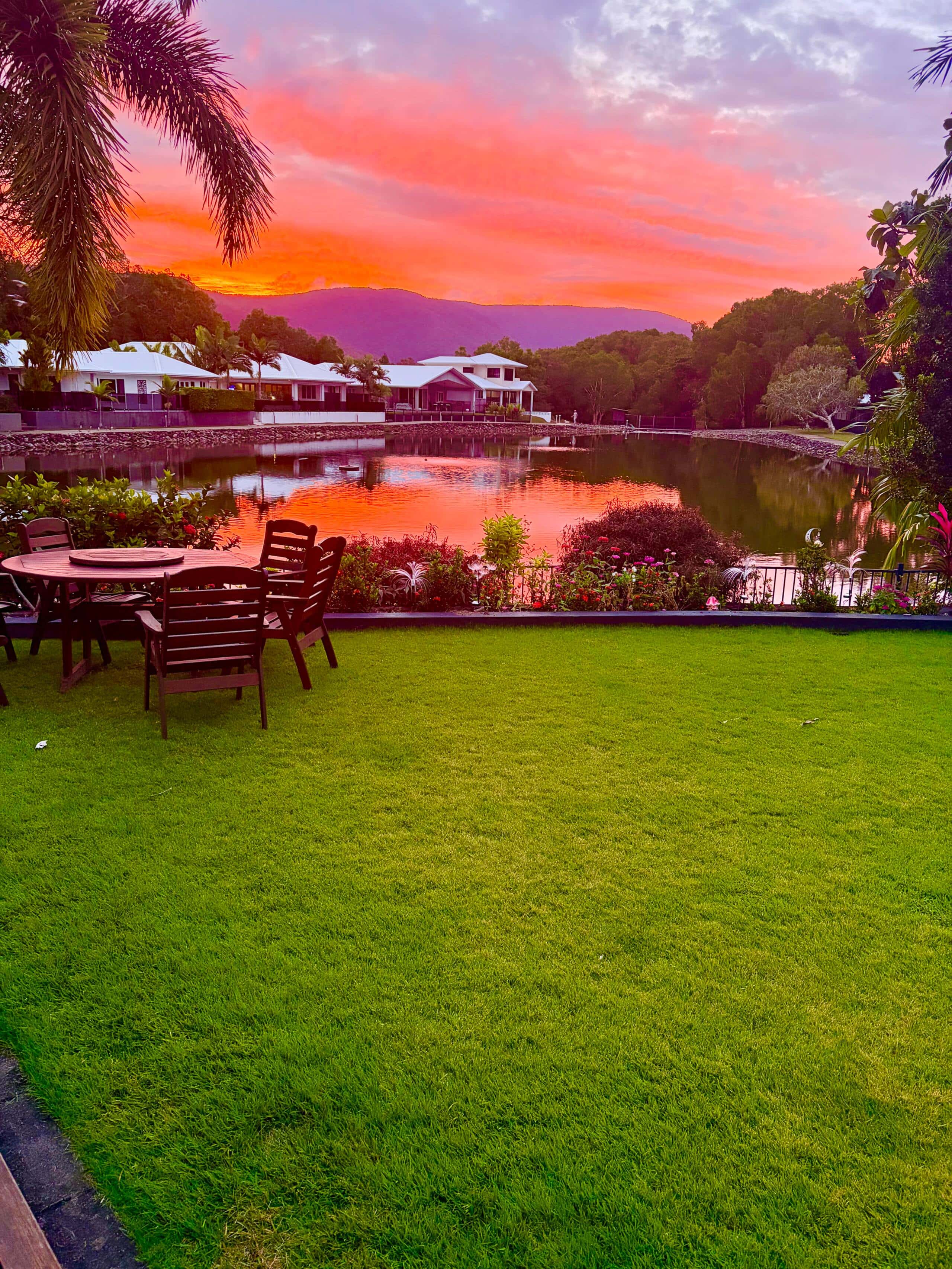 Pink and orange sunset over the lagoon from the back lawn with outdoor dining table