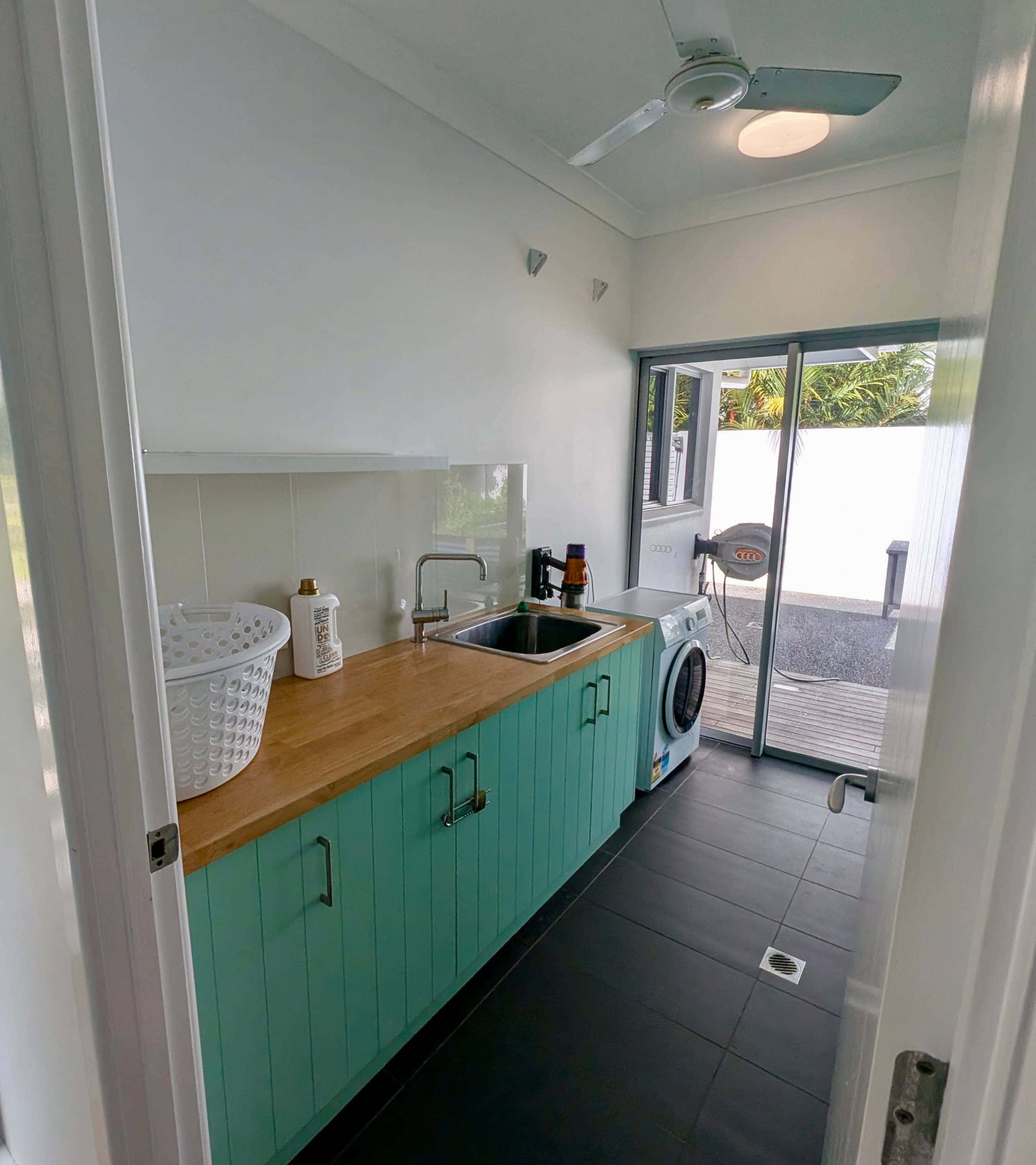 Laundry with mint cabinetry, timber benchtop and washing machine opening to the drying courtyard