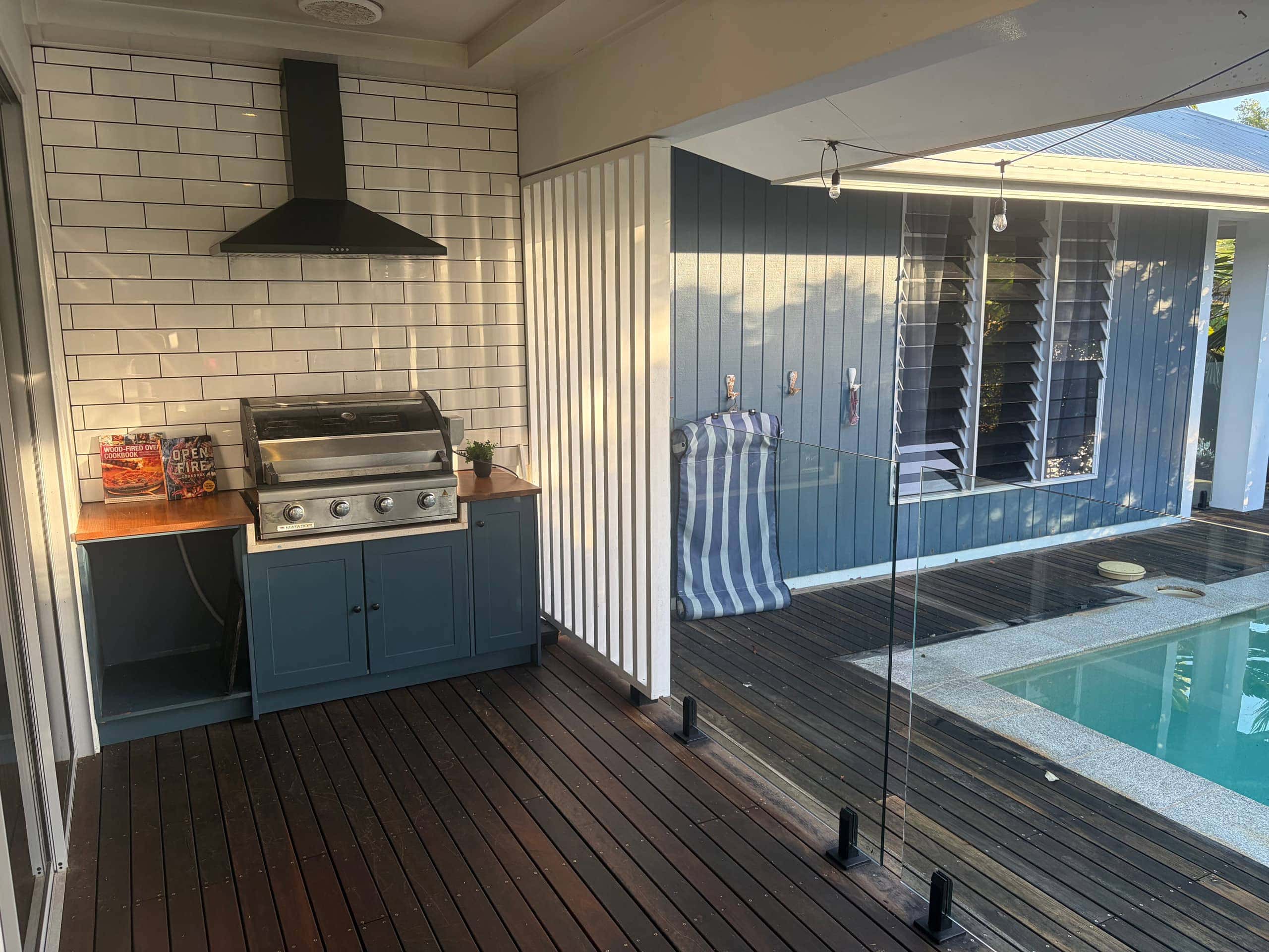 Poolside barbecue nook with four-burner grill, rangehood and subway tiles beside the pool deck